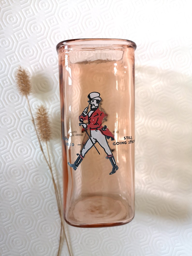 Peut inclure: Un verre &agrave; boire en verre rose avec une image imprim&eacute;e d'un homme en veste rouge et pantalon blanc marchant avec une canne. Le texte "Still Going Strong" est imprim&eacute; sur le verre.