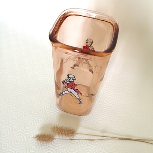 Peut inclure: Un verre &agrave; boire en verre transparent de forme carr&eacute;e avec une teinte rose. Le verre est orn&eacute; d'une image imprim&eacute;e d'un homme en manteau rouge et pantalon blanc, tenant une canne. Le texte "Still Going Strong" est imprim&eacute; sur le verre.