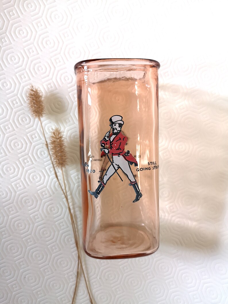 Peut inclure: Un verre en verre rose avec une image imprim&eacute;e d'un homme en veste rouge et pantalon blanc marchant avec une canne. Le texte "Still Going Strong" est imprim&eacute; sur le verre.