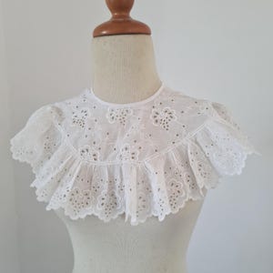 May include: White cotton lace collar with a scalloped edge and delicate floral embroidery.