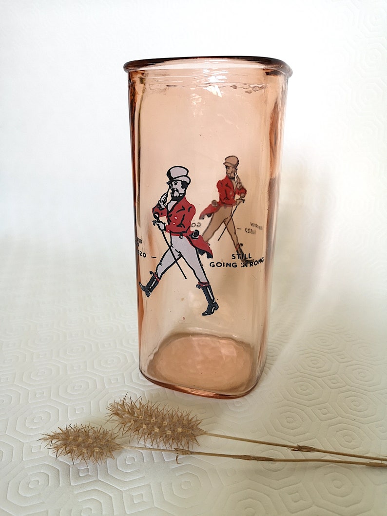 Peut inclure: Un pot en verre rose avec une image imprim&eacute;e d'un homme en veste rouge et pantalon blanc marchant avec une canne. Le texte "Still Going Strong" est imprim&eacute; sous l'image.