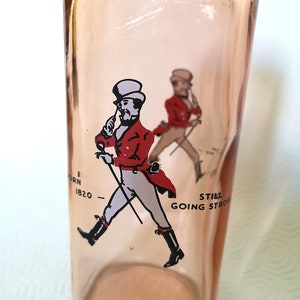 Peut inclure: Une bouteille en verre rose avec une image imprim&eacute;e d'un homme en veste rouge et pantalon blanc marchant avec une canne. Le texte "Still Going Strong" est imprim&eacute; sur la bouteille.