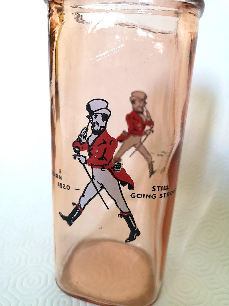 Peut inclure: Une bouteille en verre rose avec une image imprim&eacute;e d'un homme en veste rouge et pantalon blanc marchant avec une canne. Le texte "Still Going Strong" est imprim&eacute; sur la bouteille.