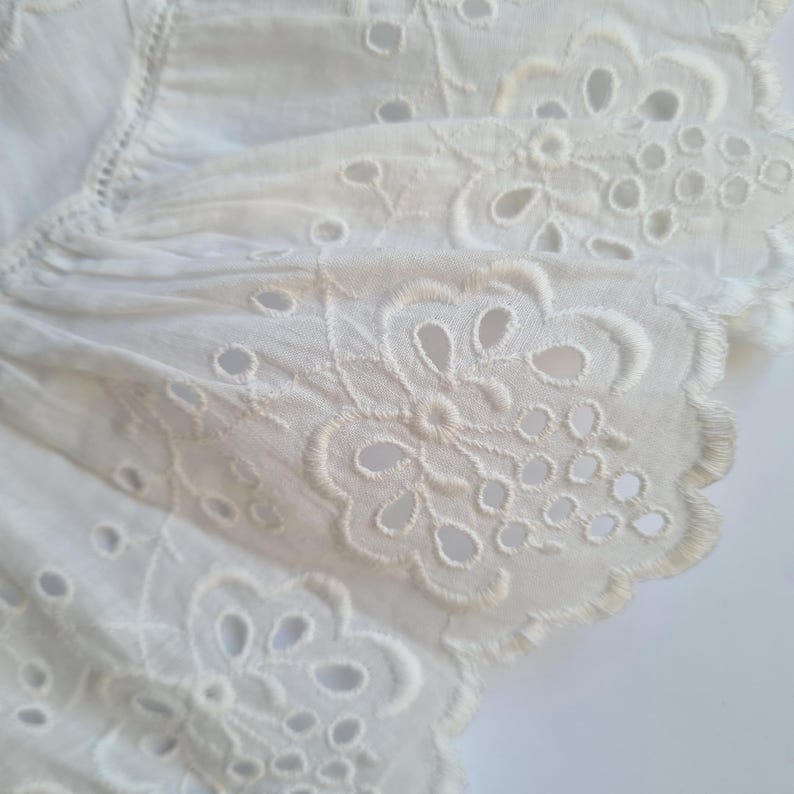 May include: White cotton lace trim with a scalloped edge and delicate floral embroidery.