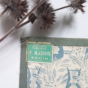 May include: A green and white label with the text "Librairie Papeterie P. Masson Montauban" on a book cover with a blue and white floral pattern.