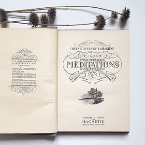May include: An open book with a cream-coloured cover and black text. The title of the book is "Les Chefs d'Oeuvre de Lamartine" and the subtitle is "Premi&egrave;res M&eacute;ditations Po&eacute;tiques". The book is printed and published by Hachette.