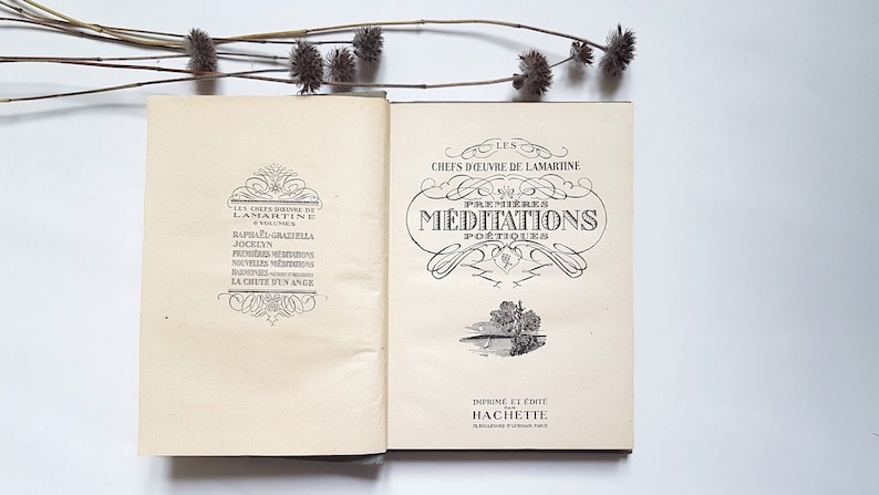 May include: An open book with a cream-coloured cover and black text. The title of the book is "Les Chefs d'Oeuvre de Lamartine" and the subtitle is "Premi&egrave;res M&eacute;ditations Po&eacute;tiques". The book is printed and published by Hachette.