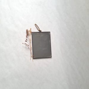 Peut inclure: Un petit cadre photo rectangulaire en métal noir avec une attache en corde. Le cadre est vide et a un léger éclat.