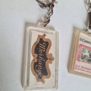 May include: A clear plastic keychain with a gold and black logo that says "Morkap" on a white background.