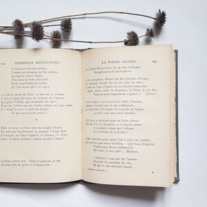 May include: An open book with cream-coloured pages and a green cover. The book is titled "Premieres Meditations" and "La Poesie Sacree". The text on the pages is in French.