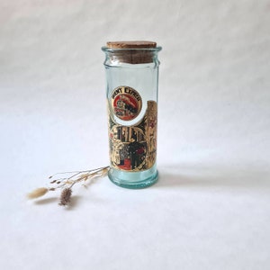 May include: A clear glass jar with a cork lid and a label that says "Orient Express" with a vintage train illustration. The jar has a blue tint and is decorated with a gold design.
