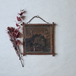 以下が含まれることがあります： 濃い茶色の木製のフレームが付いたヴィンテージの鏡。鏡には、鳥と2人の人物の白黒の画像が映っています。鏡は白い壁に掛けられています。