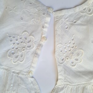 May include: White cotton dress with eyelet embroidery and a button closure in the back.
