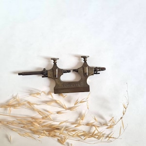 Peut inclure: Tour de bijoutier antique en laiton avec une poignée de chaque côté et l'inscription "A. ENDERLIN."