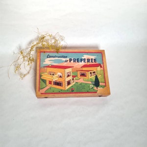 Peut inclure: Boîte en bois vintage avec une illustration colorée de deux maisons et le texte "Construction la PREFEREE".