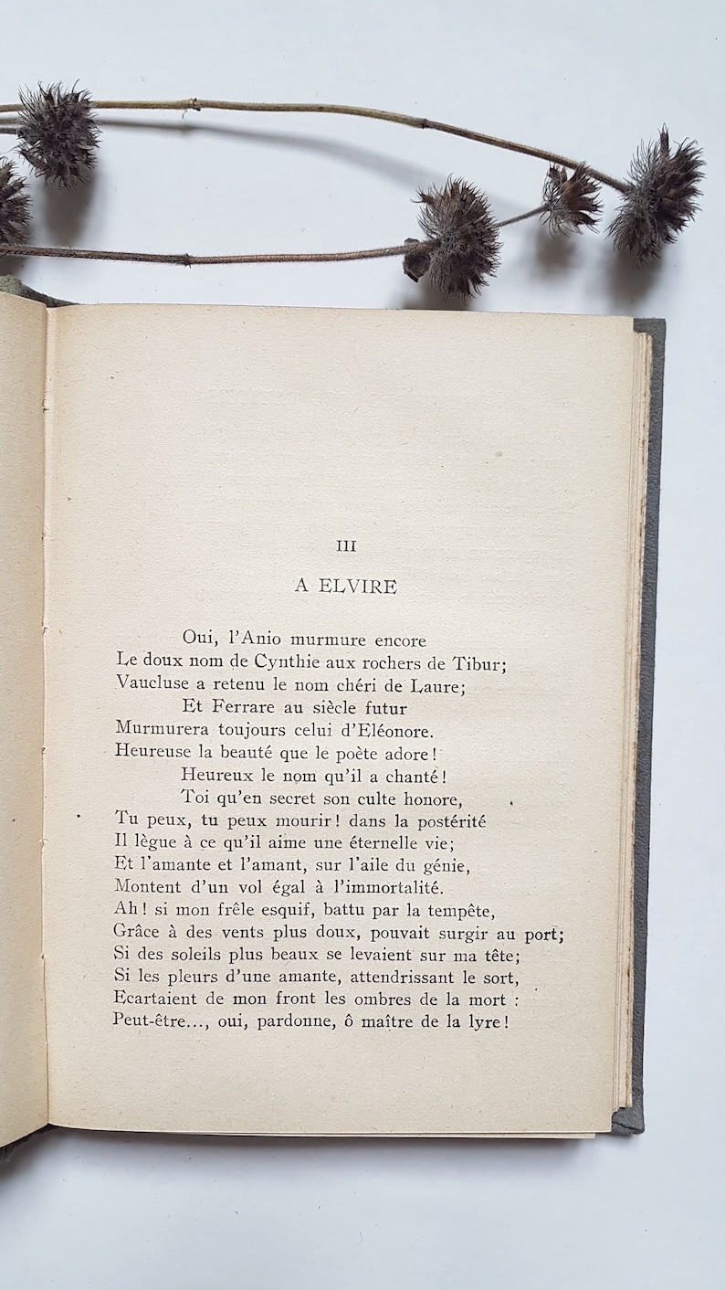 May include: A page from a book with the title "A Elvire" and text in French. The text is a poem about a woman named Elvire. The page is yellowed with age and has a worn, vintage look.