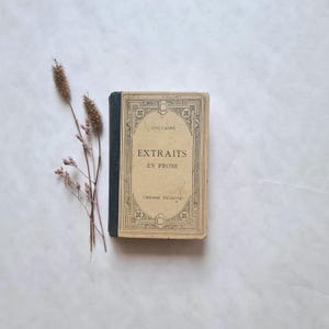 May include: A vintage book titled "Extraits en Prose" by Voltaire, published by Librairie Hachette. The book has a brown cover with a decorative black border and gold lettering.