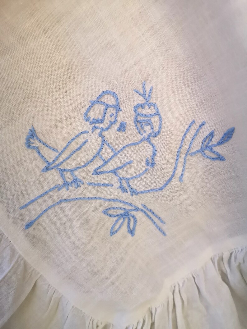 Puede incluir: P&aacute;jaros azules bordados en una rama con hojas sobre una tela de lino blanca.