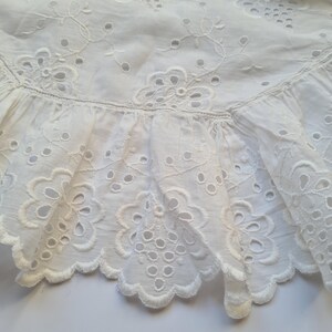 May include: White eyelet lace trim with a scalloped edge. The lace has a delicate floral pattern with small holes throughout.