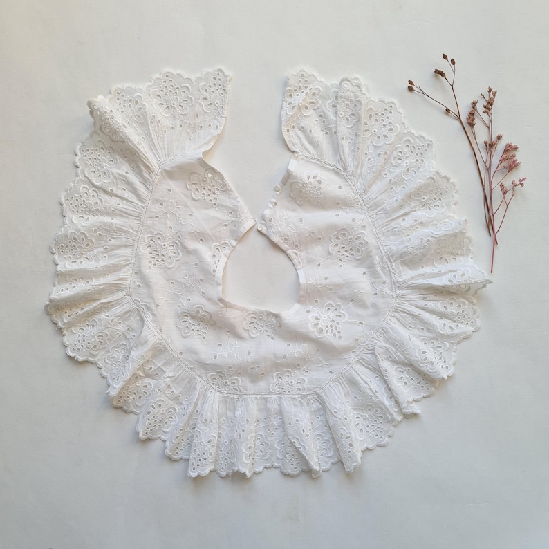 May include: White cotton lace collar with a scalloped edge and delicate floral embroidery.
