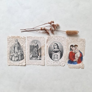 May include: Four vintage religious cards with intricate lace edges. The cards feature illustrations of religious figures, including the Virgin Mary and saints. The cards are arranged on a white surface with dried floral accents, creating a nostalgic and spiritual aesthetic.