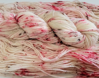 May include: A skein of white yarn with pink and brown speckles. The yarn is soft and fluffy, and it would be perfect for knitting or crocheting.