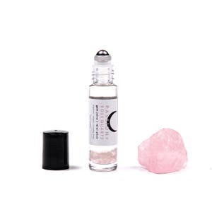 May include: A clear glass roller bottle with a silver roller ball and a white label that reads "PASSION + ROSE QUARTZ Gem Juice | mini elixir organic, vegan, cruelty free". The bottle is filled with a clear liquid and pink crystals. A pink rose quartz crystal is also pictured.