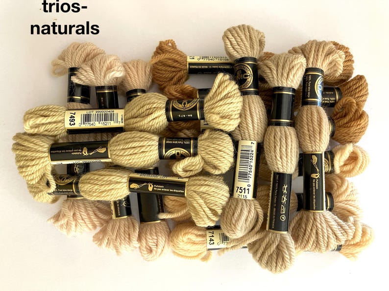 May include: A collection of skeins of natural colored embroidery floss, with labels showing the numbers 7493, 7511, and 7143.