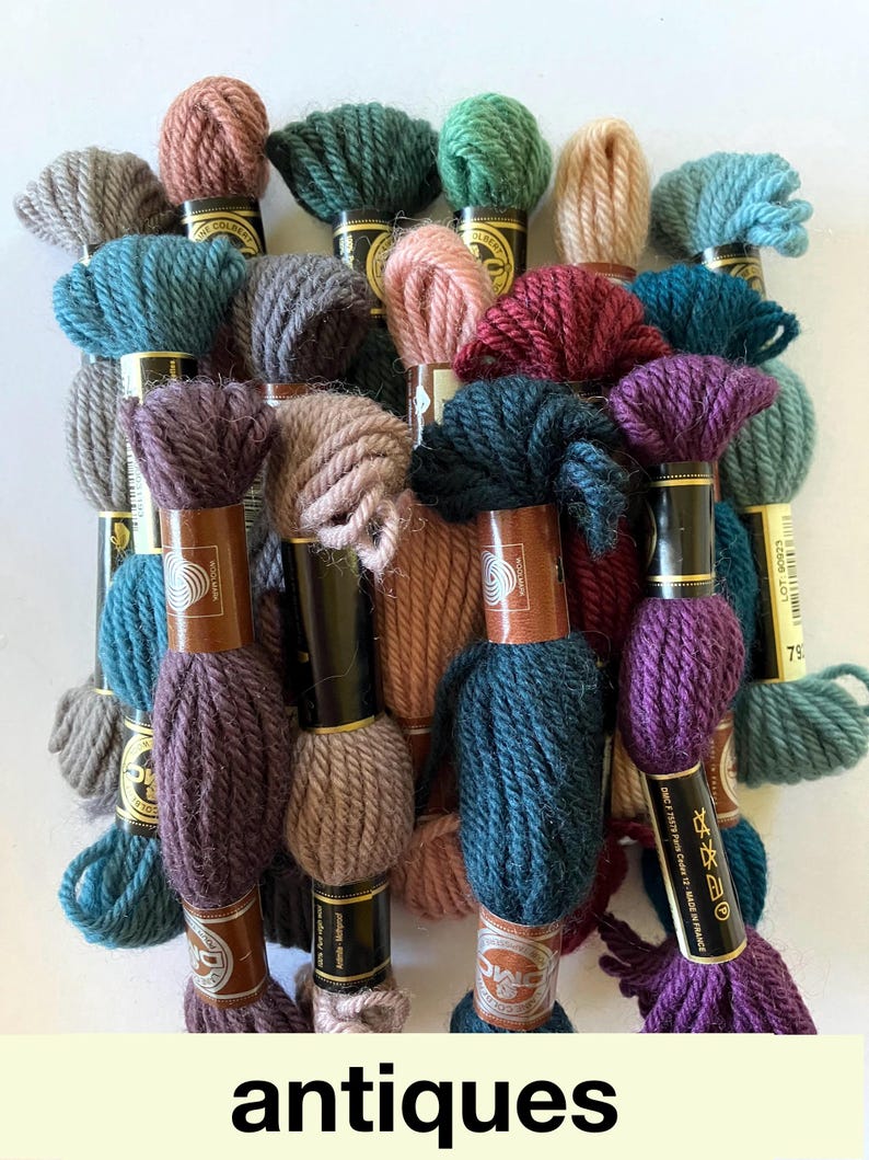 May include: Assortment of DMC embroidery floss skeins in various shades of green, blue, purple, brown, and pink. The skeins are wrapped around cardboard spools with gold labels and black text.