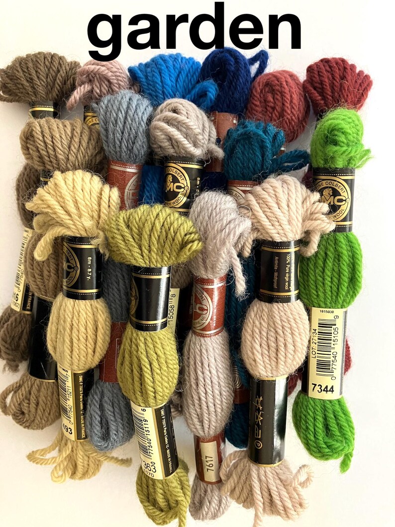 May include: A collection of 18 skeins of DMC embroidery floss in various shades of green, brown, beige, blue, and red. The skeins are arranged in a semi-circle and labeled with DMC numbers.