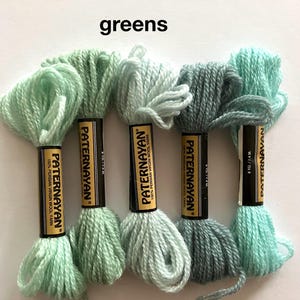 May include: A selection of green wool yarn skeins, with labels reading "PATERNAYAN 100% PERSIAN VIRGIN WOOL YARN." The shades vary from pale mint to deep teal. The word "greens" is printed at the top.