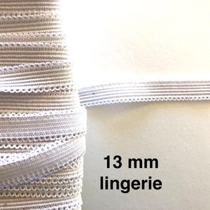 May include: A roll of white, 13 mm lingerie elastic with a scalloped edge. The elastic is tightly wound, showing the texture and detail of the material. The text "13 mm lingerie" is visible in the image.