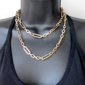 May include: A gold chain necklace with two layers of linked rectangular and round chain links.