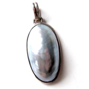 Peut inclure: Un pendentif en argent avec une grande pierre ovale en nacre blanche.