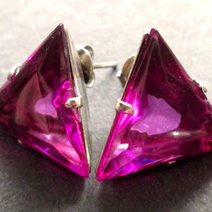 May include: A pair of silver earrings with triangular shaped pink gemstones.