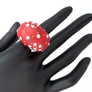 May include: A red ring with white and gold accents. The ring is shaped like a mushroom and has a textured surface.