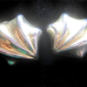 May include: A pair of gold and silver tone earrings with a fan-shaped design.