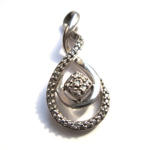 May include: A silver pendant featuring a diamond-shaped centre stone and a twisted design. The pendant is set with small diamonds around the edges.