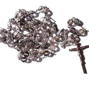May include: A silver rosary with clear glass beads and a silver crucifix.