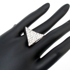 Peut inclure: Une bague en argent avec une grande pierre de forme triangulaire sertie de strass transparents.