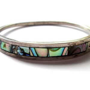 Peut inclure: Un bracelet jonc en argent avec une bande d'incrustation d'abalone iridescent.