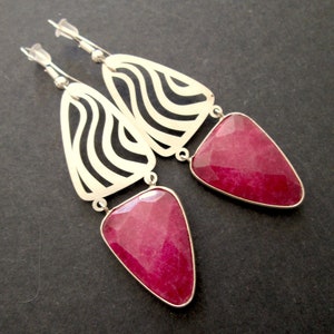 May include: Silver earrings with a geometric design and pink gemstone drops.