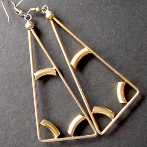 Peut inclure: Une paire de boucles d'oreilles triangulaires dorées avec des accents dorés incurvés.