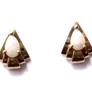 May include: A pair of gold earrings with a pear-shaped opal gemstone set in a triangular design.