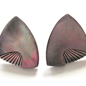 May include: A pair of iridescent, triangular earrings. Each earring has a dark grey top that fades into a pinkish hue at the bottom. A fan-like design is etched into the lower portion of each earring.