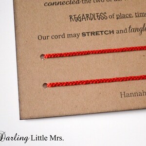 May include: A close-up of a brown card with two red cords threaded through holes. Text on the card reads "REGARDLESS of place, time, or circle" and "Our cord may STRETCH and tangle, but will". The Darling Little Mrs. is printed at the bottom.