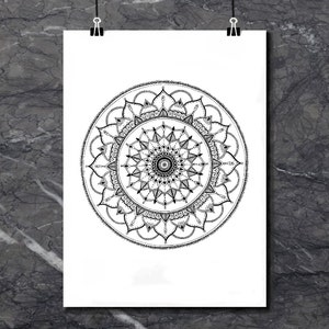 May include: A black and white mandala design with intricate details. The mandala is circular and has a symmetrical pattern.