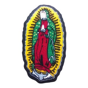 Op de afbeelding: Gestikte patch met een kleurrijke afbeelding van de Maagd Maria, omringd door een gele halo met groene sterren. De patch is op een zwarte achtergrond.