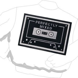 May include: A white jacket with a black patch featuring a cassette tape design. The patch has the words "PERFECTLY MIXED" in white lettering. The cassette tape design is in silver and black.