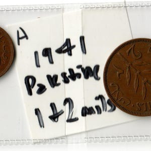 May include: Two brown Palestine coins, one with the inscription "ONE MIL" and a sprig design, and the other with "2 MILS". A handwritten note reads "1941 Palestine 1+2 mils".